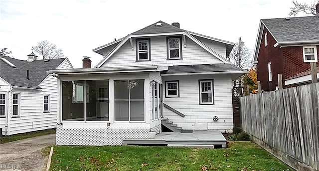 rear view of property with a lawn and a sunroom