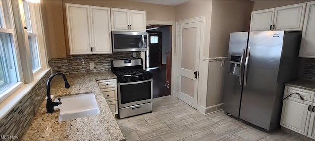 kitchen featuring white cabinetry, light stone countertops, sink, and stainless steel appliances