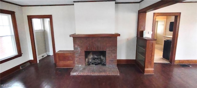 unfurnished living room with dark hardwood / wood-style floors, a healthy amount of sunlight, crown molding, and a brick fireplace