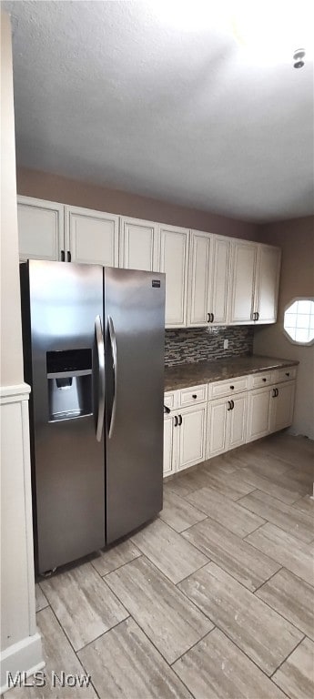 kitchen with white cabinets, stainless steel fridge, light hardwood / wood-style floors, and tasteful backsplash