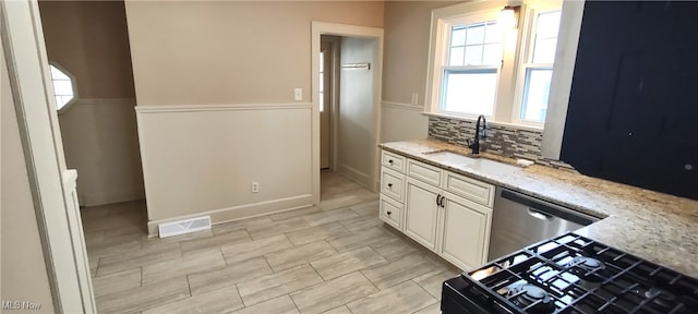 kitchen featuring white cabinetry, sink, stainless steel appliances, tasteful backsplash, and light stone counters