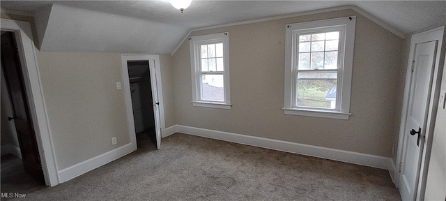 unfurnished bedroom featuring a textured ceiling, light colored carpet, and vaulted ceiling