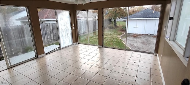 unfurnished sunroom with ceiling fan