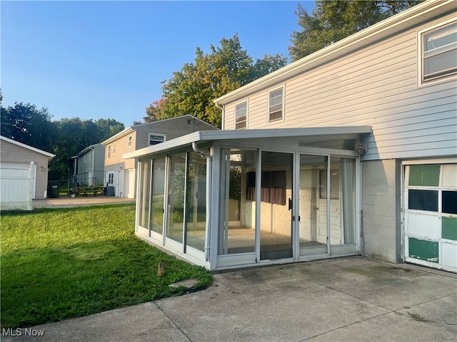 back of property with a patio area, a yard, and a sunroom