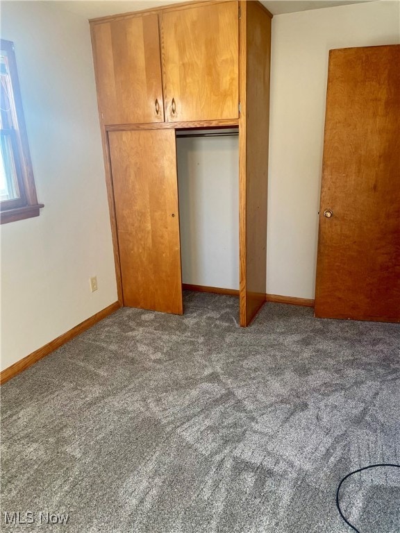 unfurnished bedroom with a closet and dark colored carpet