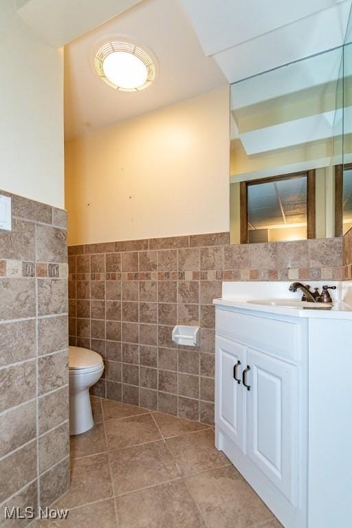 bathroom with tile patterned floors, vanity, toilet, and tile walls