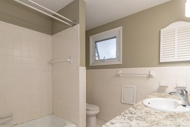 full bathroom with tiled shower / bath combo, tile patterned flooring, toilet, vanity, and tile walls