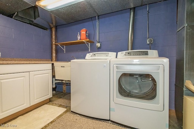 clothes washing area with cabinets and separate washer and dryer