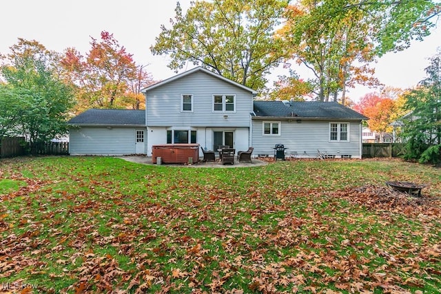 rear view of property with a yard, a patio, and a hot tub