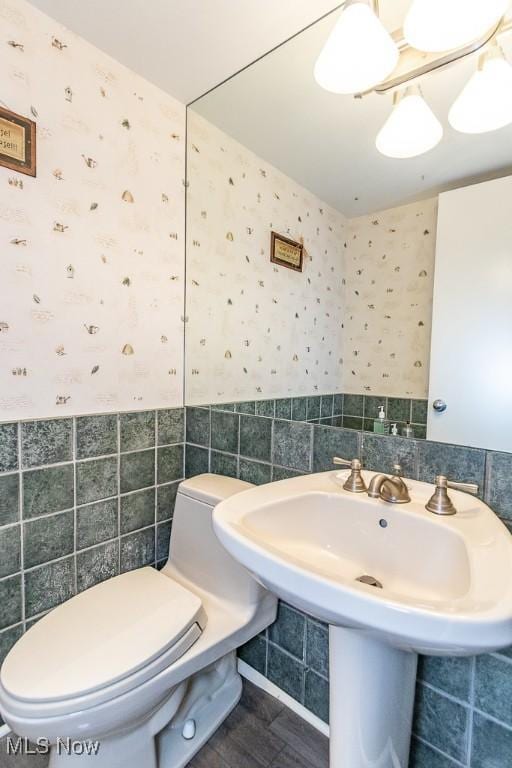 bathroom featuring sink, tile walls, and toilet