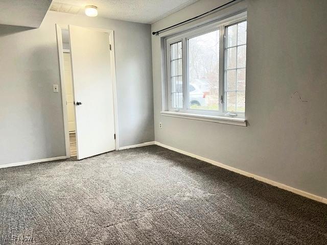 unfurnished room with carpet, a healthy amount of sunlight, and a textured ceiling