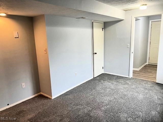 basement featuring dark carpet and a textured ceiling