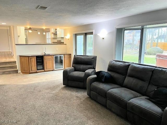 living room with a textured ceiling, a wealth of natural light, and beverage cooler