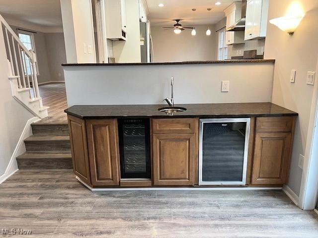 bar with stainless steel refrigerator, beverage cooler, wall chimney exhaust hood, and sink