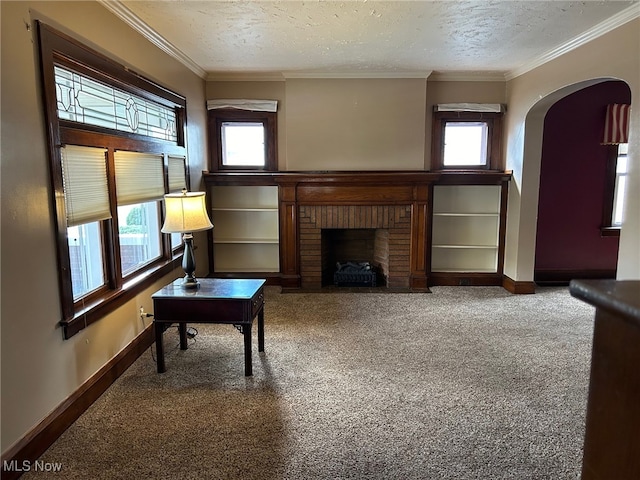 carpeted living room with a textured ceiling, a healthy amount of sunlight, and a brick fireplace