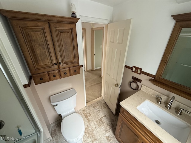 bathroom with a shower with door, vanity, and toilet