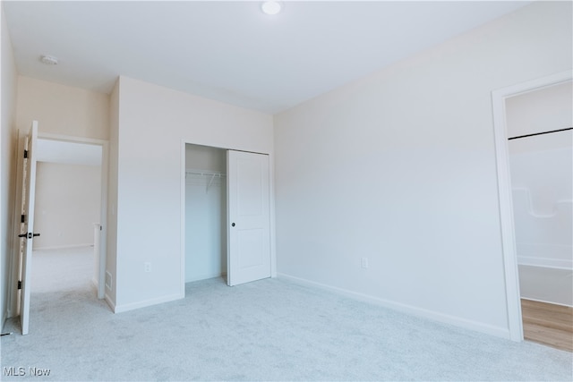 unfurnished bedroom with a closet and light carpet