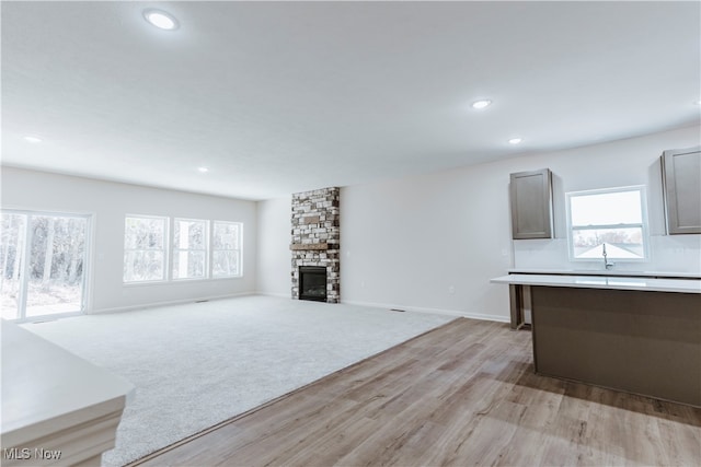 unfurnished living room with light hardwood / wood-style floors, a healthy amount of sunlight, and a fireplace