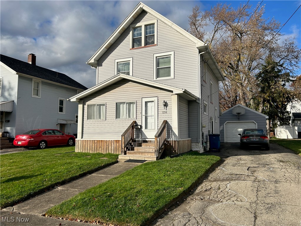 front of property with a front lawn, a garage, and an outdoor structure