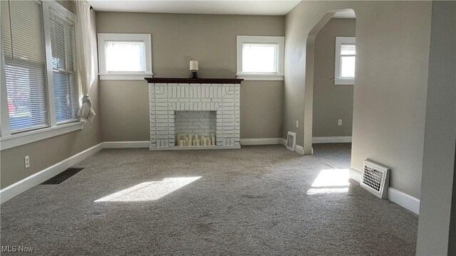 unfurnished living room featuring a fireplace, carpet floors, and plenty of natural light