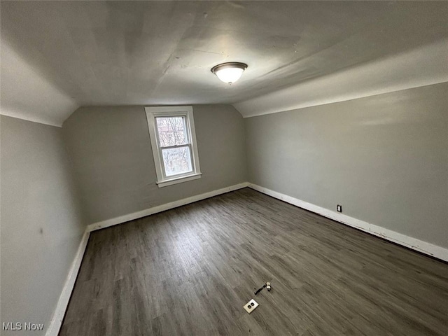 bonus room featuring dark wood-type flooring, baseboards, and lofted ceiling