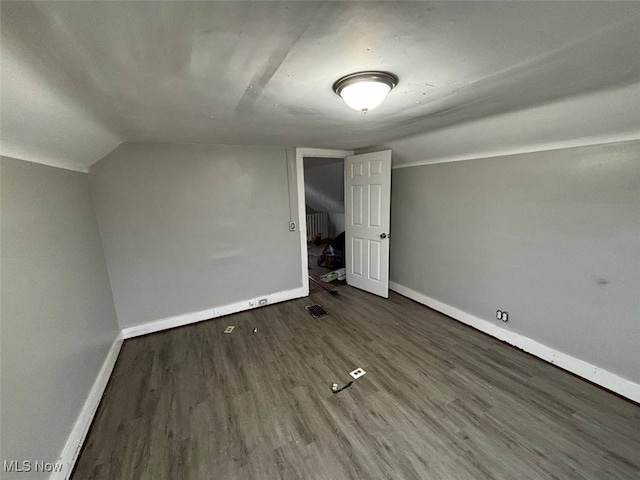 additional living space with dark hardwood / wood-style flooring and vaulted ceiling