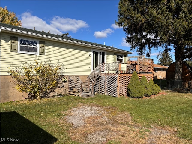 back of house with a wooden deck and a lawn