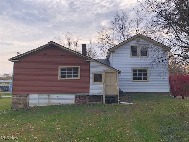 back house at dusk featuring a yard