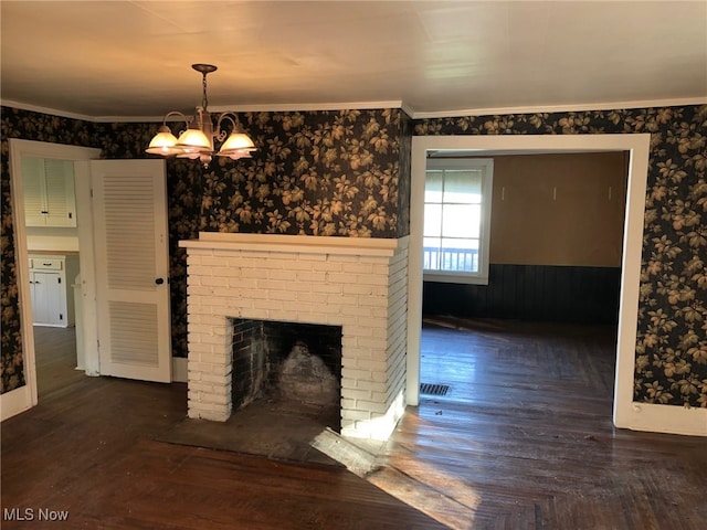 unfurnished living room featuring a notable chandelier, crown molding, a brick fireplace, and dark hardwood / wood-style floors