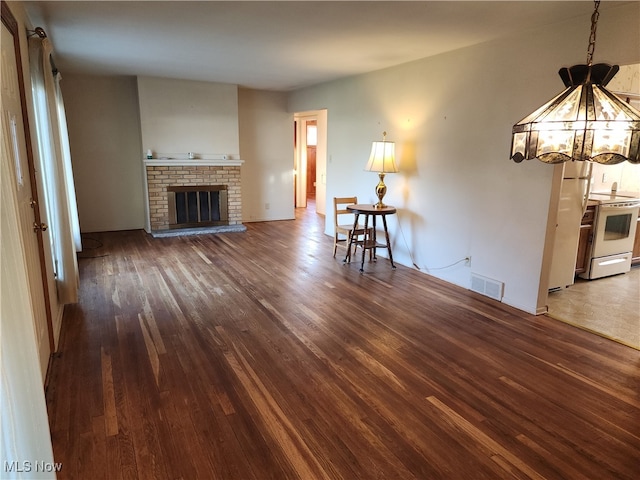 unfurnished living room with dark hardwood / wood-style floors and a brick fireplace