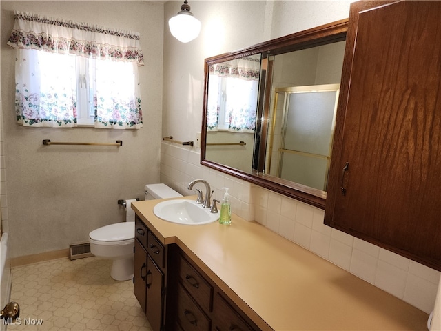 bathroom featuring vanity, toilet, a shower with shower door, and backsplash