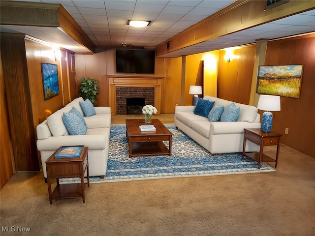 living room with wood walls, carpet, and a brick fireplace