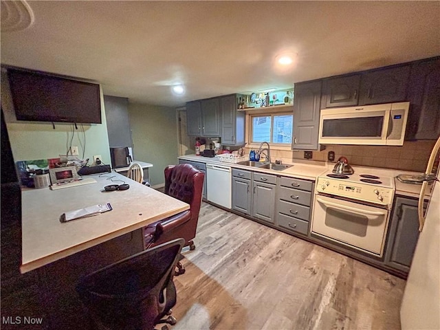 kitchen with gray cabinetry, sink, white appliances, and light hardwood / wood-style flooring