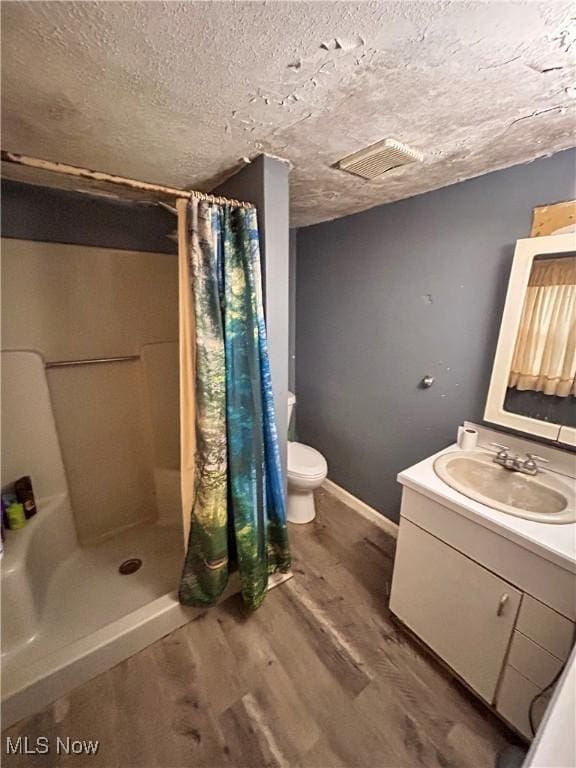 bathroom with vanity, a shower with curtain, toilet, a textured ceiling, and wood-type flooring