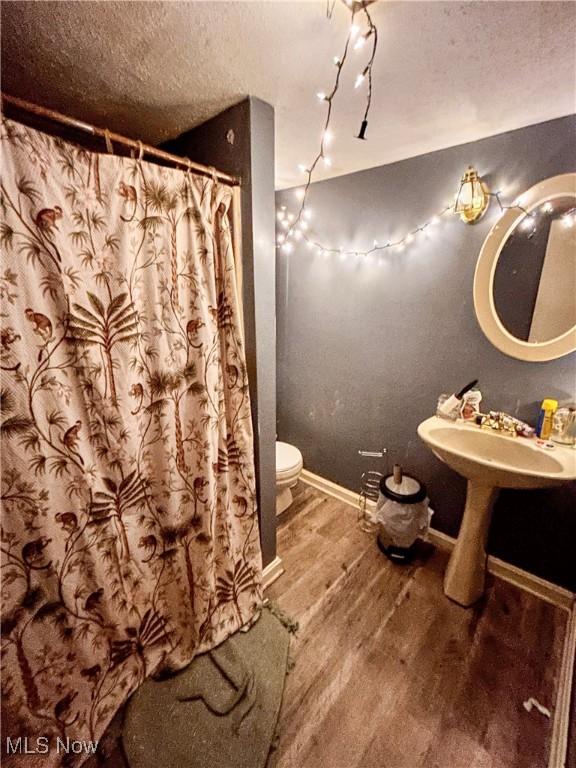 bathroom featuring wood-type flooring, a textured ceiling, and toilet