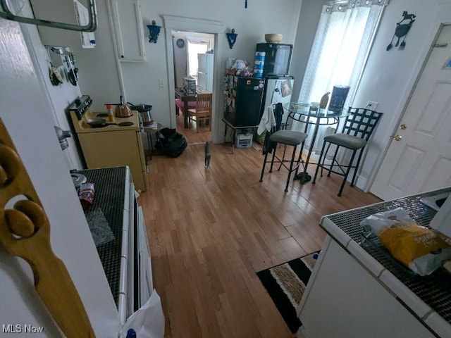 kitchen with white range with electric stovetop, white cabinetry, and light wood-type flooring