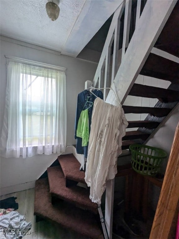 stairs featuring baseboards, a textured ceiling, and wood finished floors