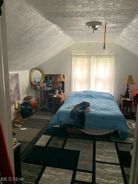 bedroom with a textured ceiling, carpet, and vaulted ceiling