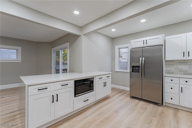 kitchen featuring stainless steel fridge with ice dispenser, black microwave, light hardwood / wood-style flooring, and white cabinetry