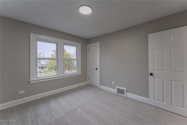 carpeted spare room with a textured ceiling