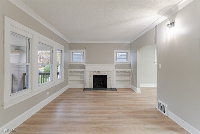 unfurnished living room featuring a textured ceiling, light hardwood / wood-style flooring, a fireplace, and ornamental molding