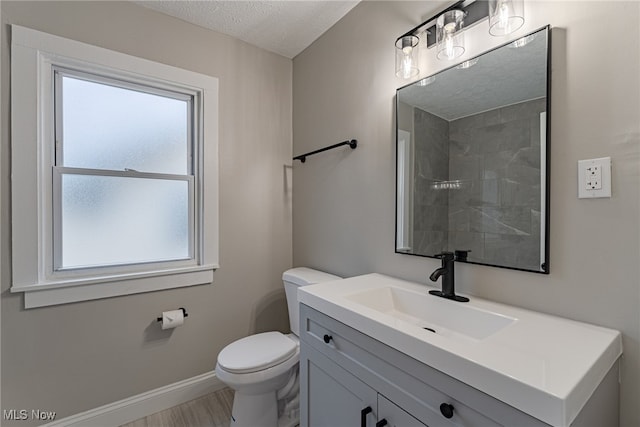 bathroom featuring vanity, toilet, a textured ceiling, and plenty of natural light