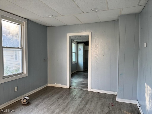 empty room with wood finished floors, baseboards, and a paneled ceiling