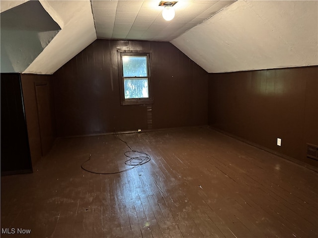 additional living space with lofted ceiling, wooden walls, and dark hardwood / wood-style floors