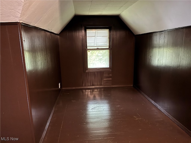 bonus room featuring wooden walls, vaulted ceiling, and dark hardwood / wood-style flooring