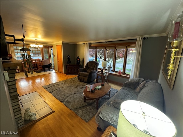 living room featuring ornamental molding, a notable chandelier, and light hardwood / wood-style floors