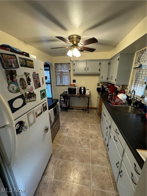 kitchen featuring sink, light tile patterned floors, ceiling fan, stainless steel range with electric stovetop, and white refrigerator