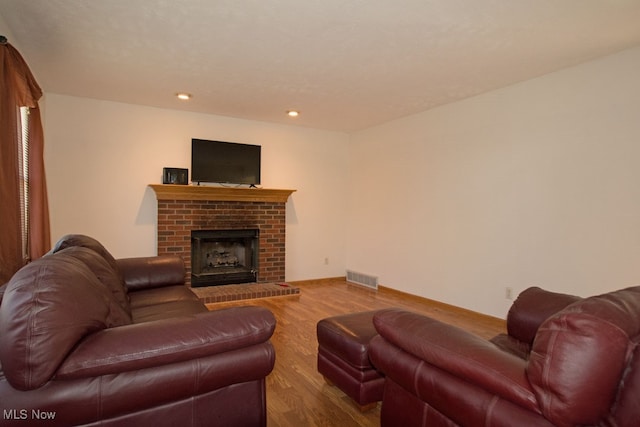 living room with hardwood / wood-style floors and a brick fireplace