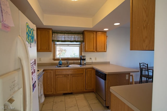 kitchen with a raised ceiling, kitchen peninsula, sink, and white appliances