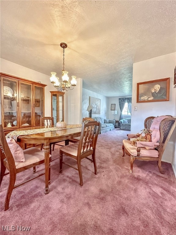 dining space featuring an inviting chandelier, a textured ceiling, and carpet flooring